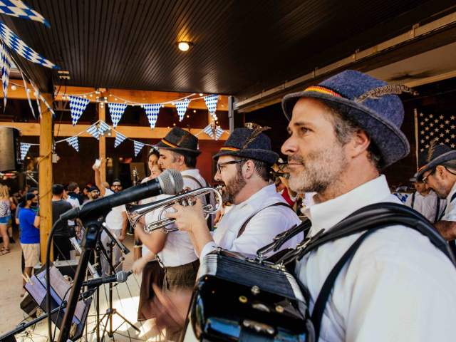 Brass and accordion players of a band in traditional German clothing on outdoor stage at Bangers Biergarden