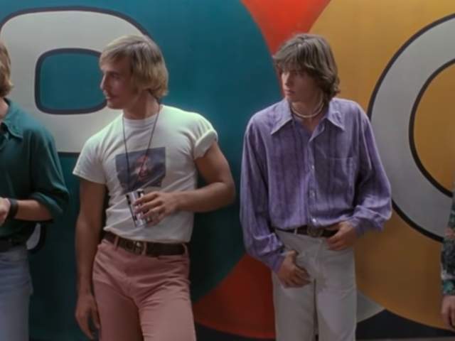 Screengrab from Dazed and Confused showing actors Sasha Jensen, Matthew McConaughey, Jason London and Wiley Wiggins standing up against the wall at the Emporium