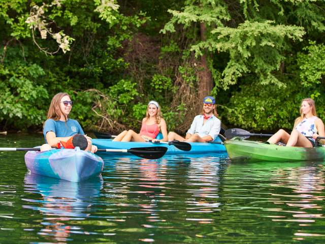 Photo of four people relaxing on the water in rental kayaks from Rowing Dock