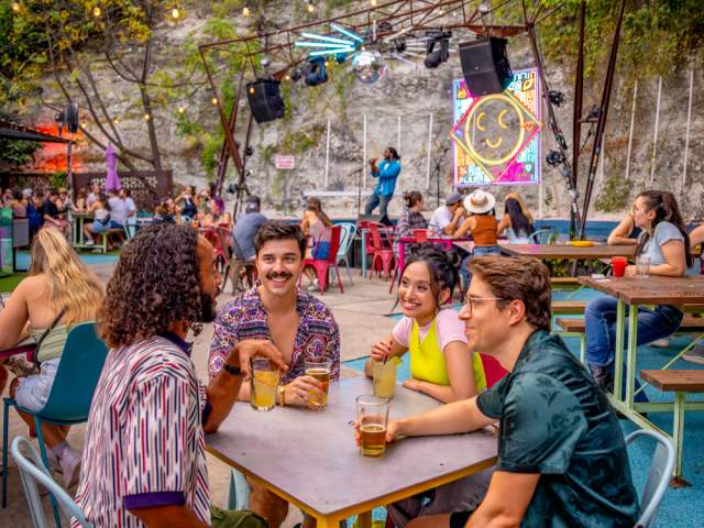 A group of men and women sitting at a table talking on the patio at Cheer Up Charlies.