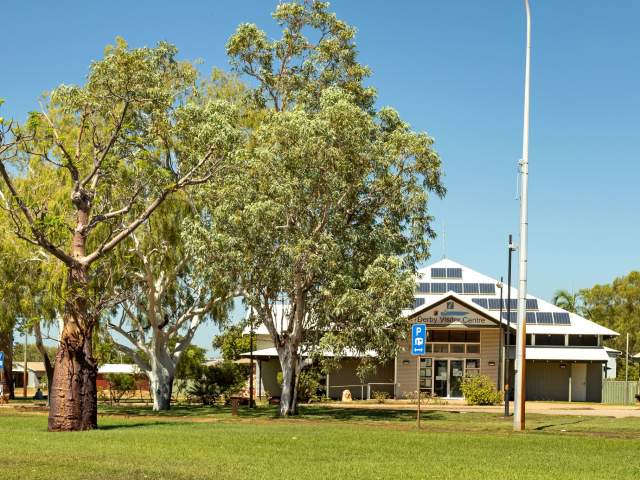 Exterior view of Derby Community Centre & Visitor Information with boab trees and an interpretative panel for the Heritage Trail