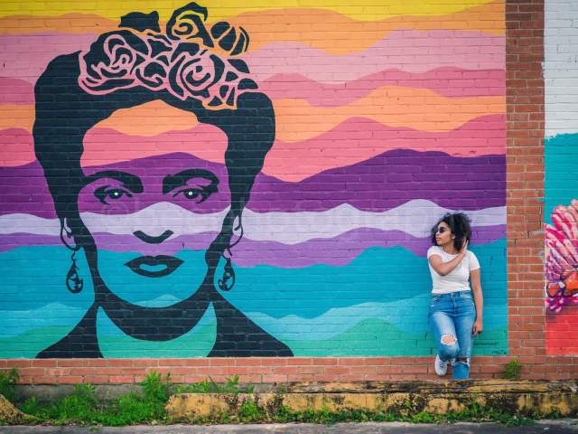Woman leaning on the wall next to the Frida Kahlo mural in downtown Beaumont