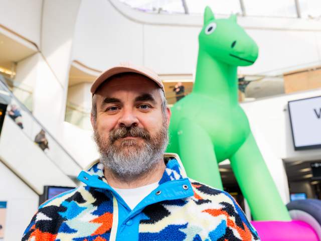 Bruce Asbestos stands with his inflatable sculpture in the middle of Grand Central station.