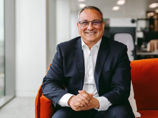 Neil Rami sat on an orange sofa in the office, smiling towards the camera