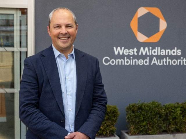 Ed Cox standing beside a sign for the West Midlands Combined Authority