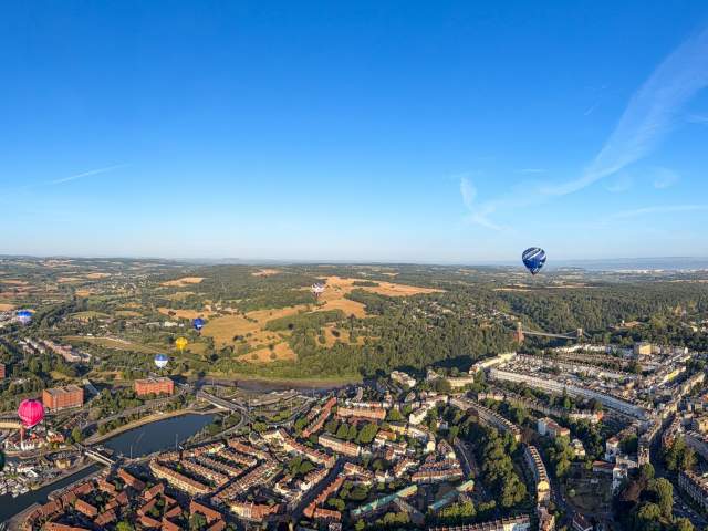 A panoramic ariel view over Bristol with multiple hot air balloons