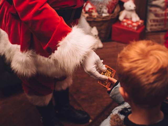 A Santa hand handing a small gift to a child - Credit Avon Valley Adventure and Wildlife Park