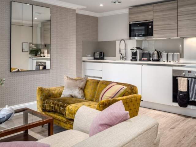 A yellow sofa in the kitchen of Beech House - Credit Urban Apartments