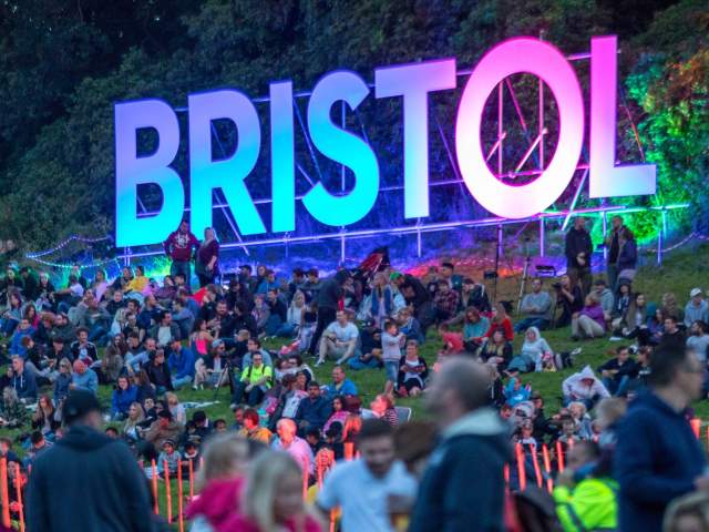 People sitting around a luminous Bristol sign at Bristol International Balloon Fiesta - credit Paul Box