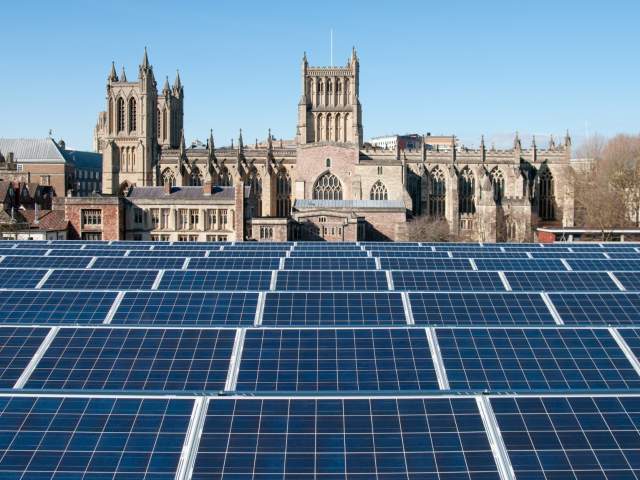 Solar panels on the roof of the We The Curious science centre on Millennium Square on Bristol's Harbourside, with Bristol Cathedral in the background - credit We The Curious