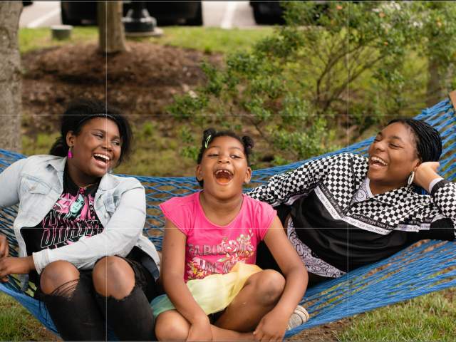three girls swinging and laughing in a hammock