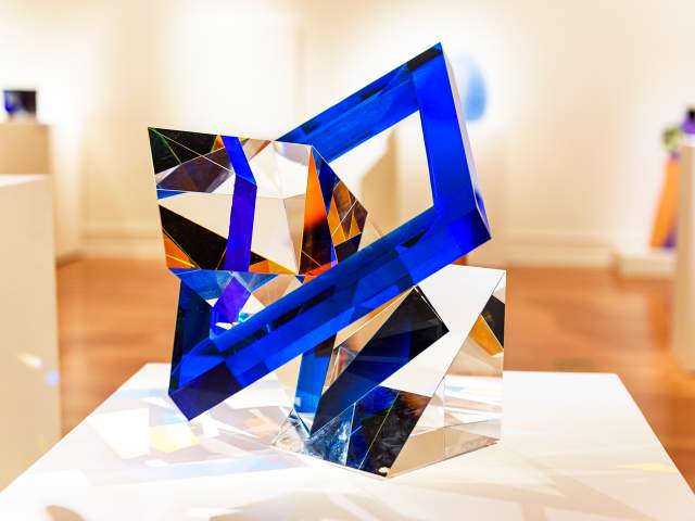glass sculpture with a blue square outer ring and transparent geometric shapes inside