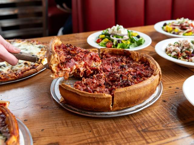 A full table of Italian food, including deep dish pizza, salad, appetizers, and dessert. At Giordano's in Fort Wayne