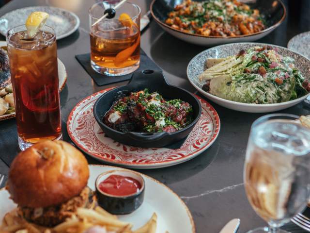 A table full of tasty dinner options from Amor&eacute; in downtown Fort Wayne. Setting includes drinks, salads, sandwhich, and pasta dishes.