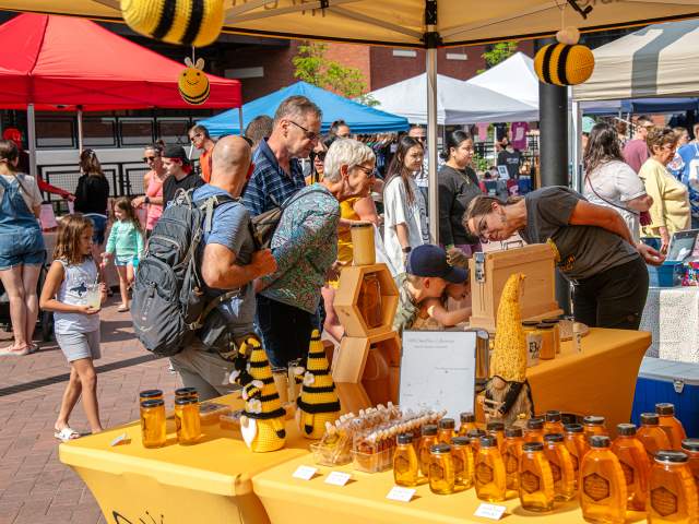 Patrons look over honey offerings at the Summit City Farmers Market at Electric Works in Fort Wayne