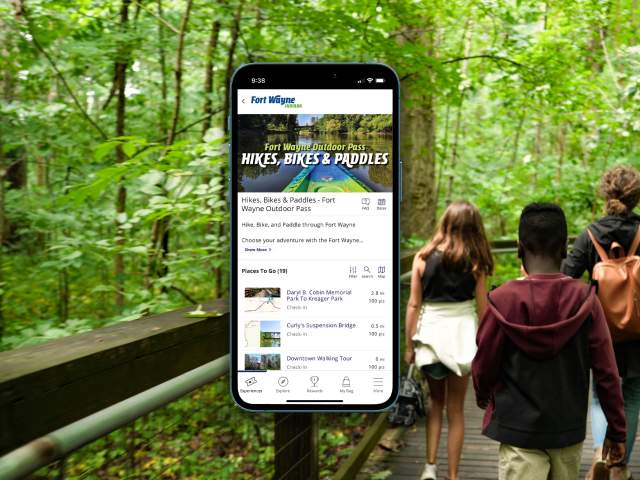 Fort Wayne Outdoor Pass on phone with a family hiking in the background.