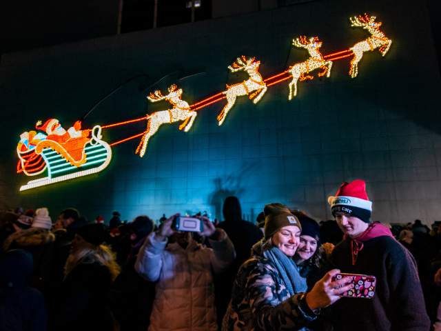 Family taking a selfie with the PNC Santa display at Night of Lights