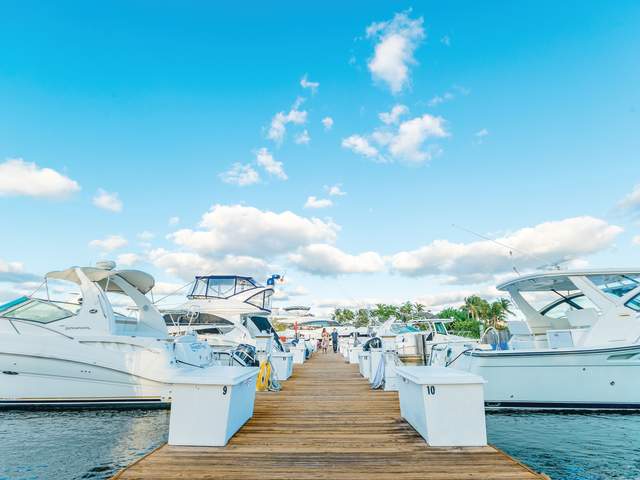 A couple walk a dock lined with boats near Nauti Dog in Lighthouse Point