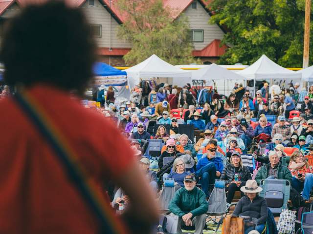 A crowd of people listen to music at Moab's Folk Festival.