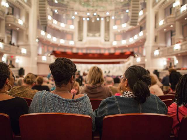 Row of people sitting in spacious Palladium Theater ready for performance to begin