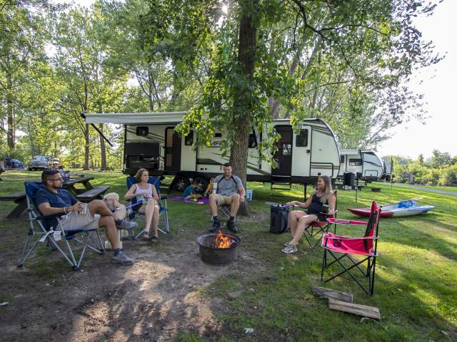 Family around fire pit ourside their RV at the Trading Post Outfitters Camp Grounds in Mango, Indiana