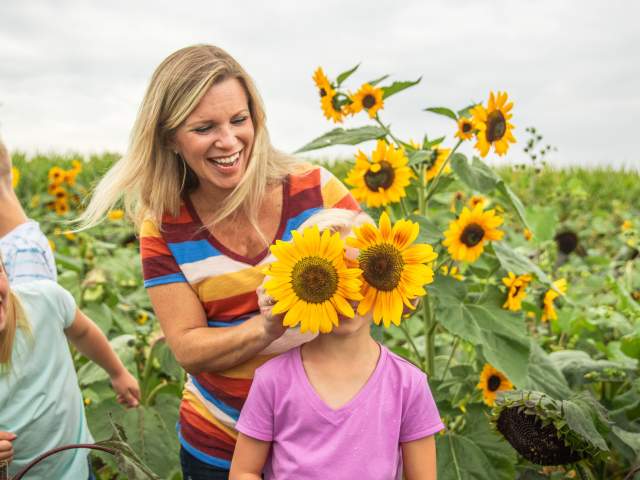 Mother holding sunflowers over daugthers eyes during a photo