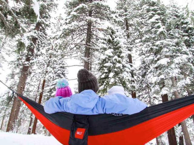 People sitting in a hammock in the snowy woods