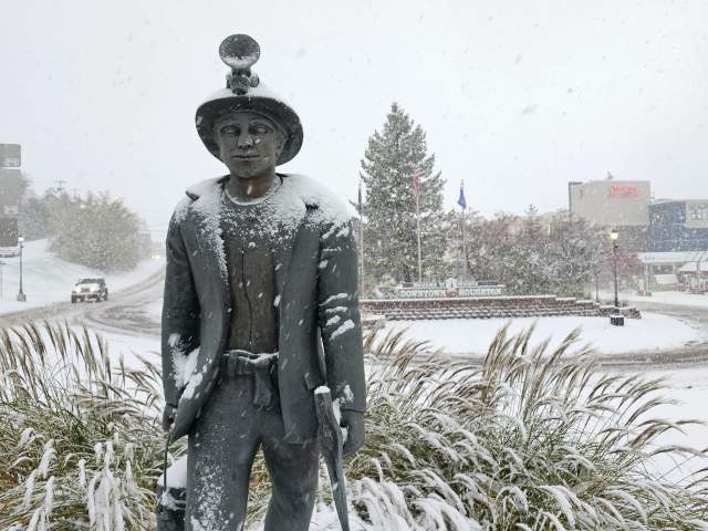 a statue of a miner stands in a snowy landscape