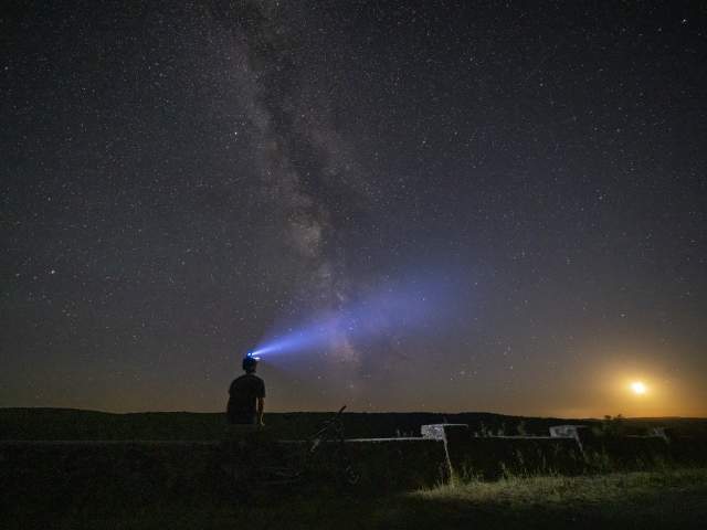 Person with headlamp looking into dark sky