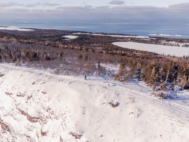 Aerial of snowshoers atop Mount Baldy with Lake Superior in background