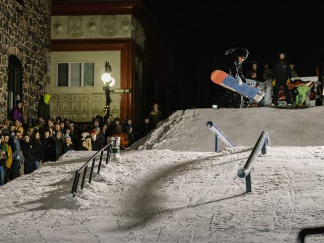 a snowboarder catches air in a downtown snow feature