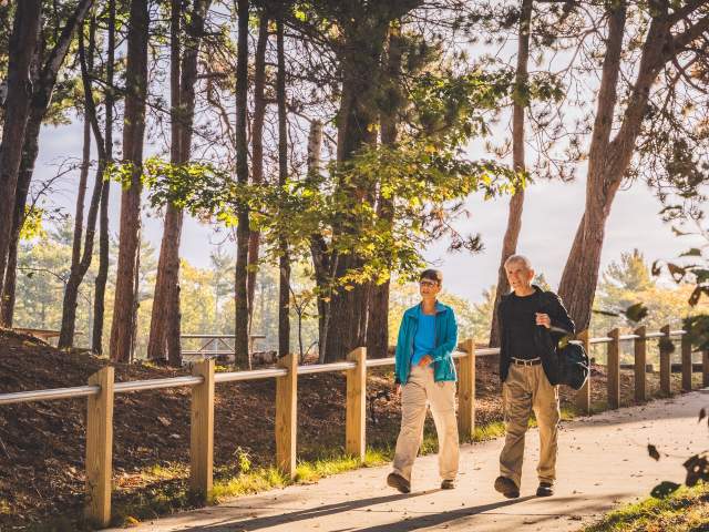 A couple walks through a sunlit path in McLain State Park.