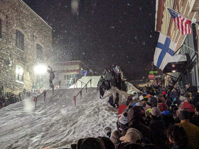 snowboarder hits a jump in view of a crowd