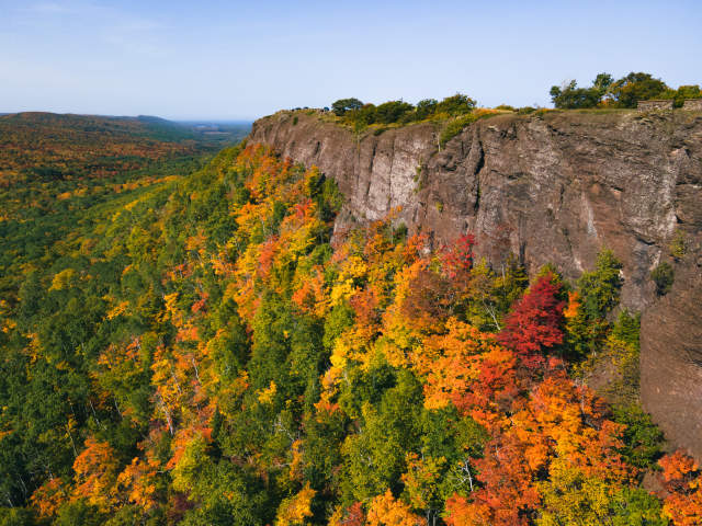 Brockway Mountain cliff face with a blend of green, yellow, orange, and red trees.