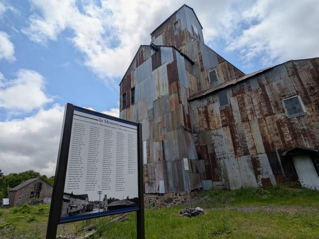 a sign stands in front of a historic rock shaft house