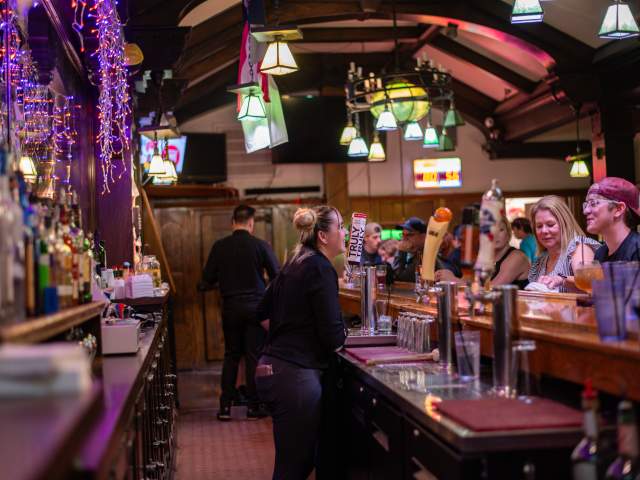 inside a lively bar patrons talk with their bartender