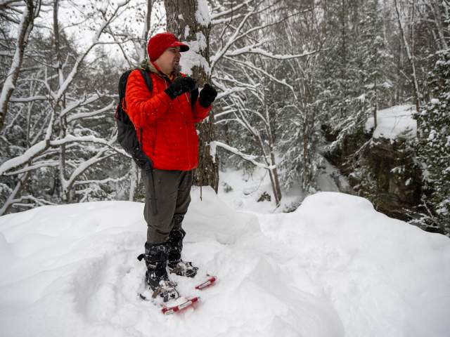 a guide in a bright coat speaks while standing in snowshoes