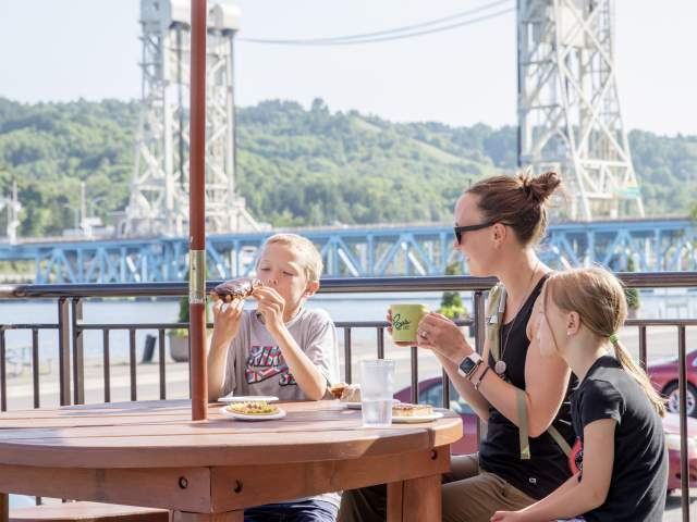 Family of three sitting on Roy's patio eating donuts.
