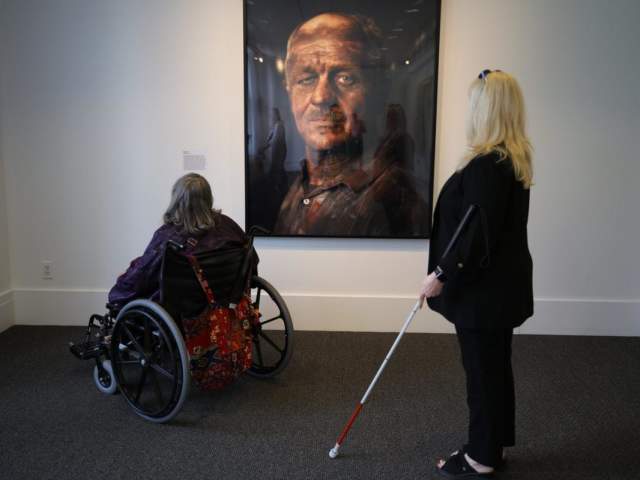 Two women look at art on the wall