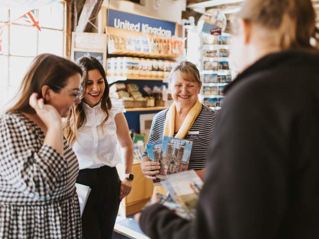 4 people stood in a group in a visitor information centre looking at leaflets