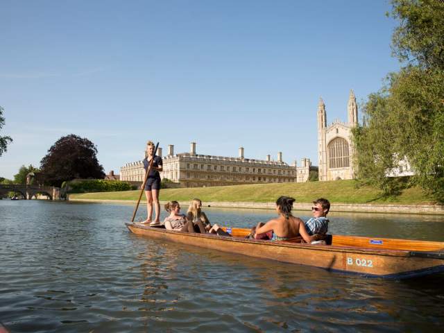 A punt boat with tourists on the River Cam with King's College Chapel in the background.