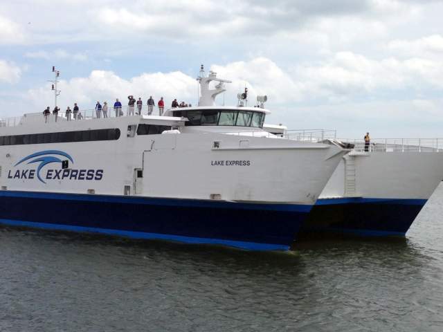 Lake Express high-speed ferry traveling across Lake Michigan with passengers standing on the upper deck.