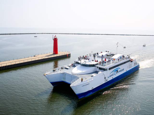 Lake Express high-speed ferry traveling across Lake Michigan with passengers standing on the upper deck.