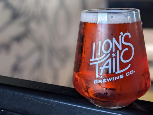 Glass of amber beer bearing the Lion’s Tail Brewing Co. logo.