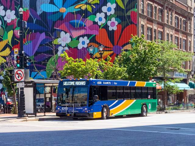 Milwaukee County Transit Bus driving along Wisconsin Avenue with a floral mural in the background