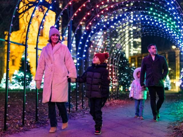 Family holding hands walking through the Milwaukee Holiday Lights Festival