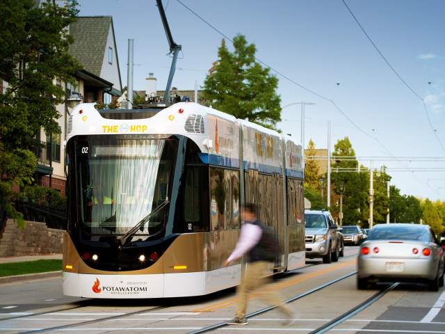 street car on road, cars and pedestrians passing