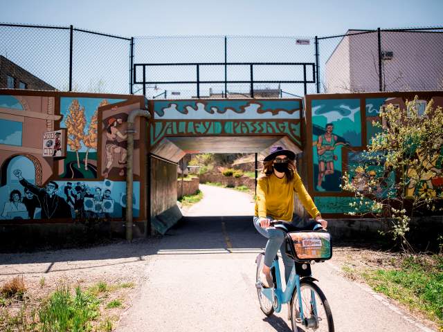 woman biking under Valley Passage Bridge