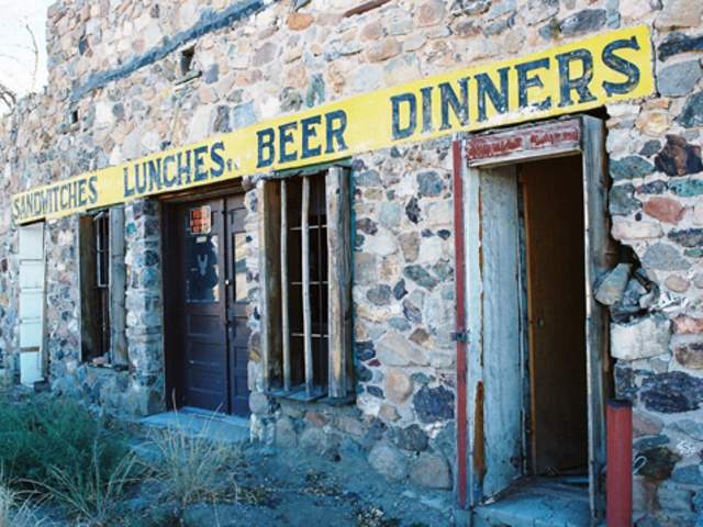 A building with a sign for "SANDWICHES. LUNCHES. BEER. DINNERS." in Organ, NM