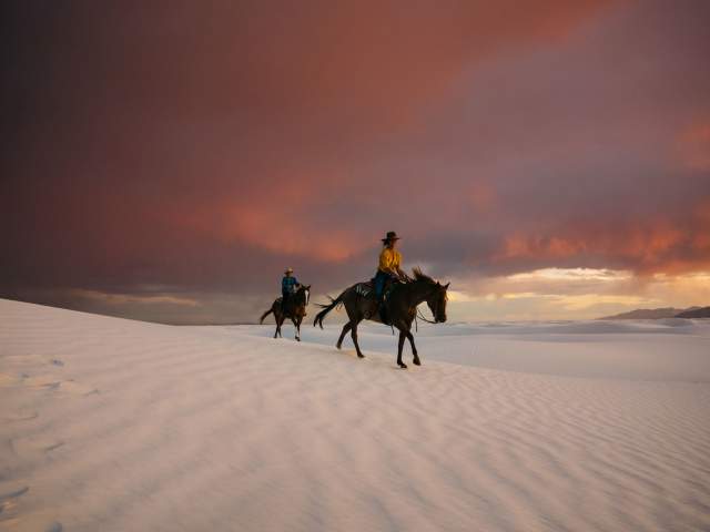 People Riding Horses In White Sands